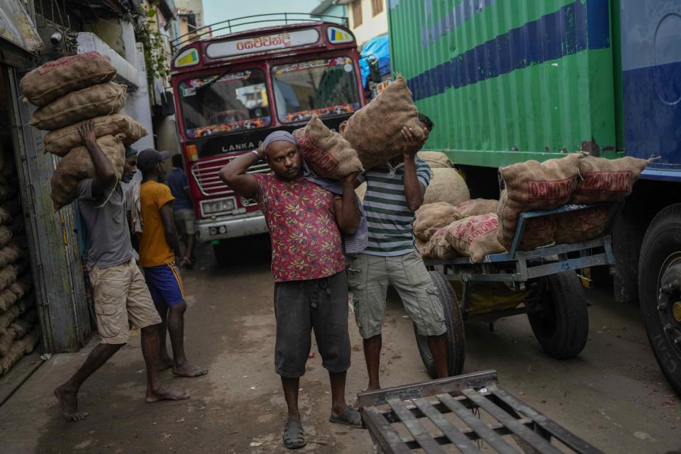 Laborers load sacks of imported potatoes to hand carts at a market place in Colombo, Sri Lanka, Tuesday, March 21, 2023. The International Monetary Fund said Monday that its executive board has approved a nearly $3 billion bailout program for Sri Lanka over four years to help salvage the country's bankrupt economy.(AP Photo/Eranga Jayawardena)