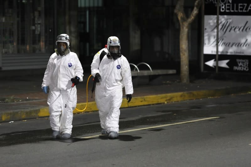 Workers in protective suits walk on the street during the national quarantine in response to the spread of coronavirus disease (COVID-19) in Caracas