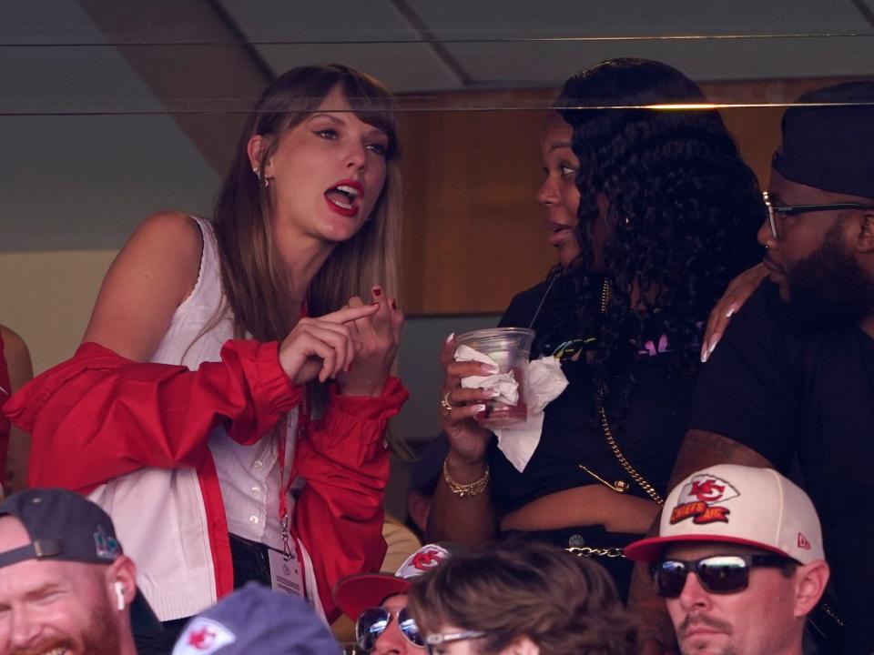 Taylor Swift speaks to a fellow spectator at the Kansas City Chiefs game.