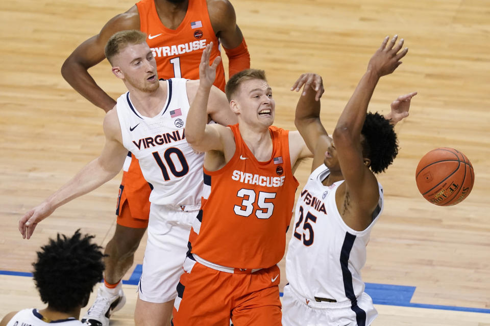 Virginia forward Sam Hauser (10) along with teammate guard Trey Murphy III (25) fight for a rebound with Syracuse guard Buddy Boeheim (35) during the first half of an NCAA college basketball game in the quarterfinal round of the Atlantic Coast Conference tournament in Greensboro, N.C., Thursday, March 11, 2021. (AP Photo/Gerry Broome)