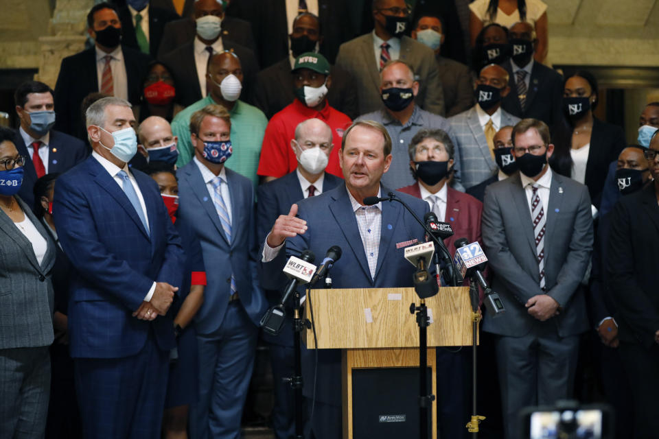 Mississippi basketball coach, Kermit Davis, center, joins other athletic staff from the state's public universities calling for a change in the Mississippi state flag, during a joint news conference at the Capitol in Jackson, Miss., Thursday, June 25,2020. Several head coaches met with both Lt. Gov. Delbert Hosemann and Speaker Philip Gunn in addition to their lawmakers, to lobby for the change by their respective bodies. The current flag has in the canton portion of the banner the design of the Civil War-era Confederate battle flag, that has been the center of a long-simmering debate about its removal or replacement. (AP Photo/Rogelio V. Solis)