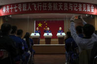 Tang Hongbo, a Chinese astronaut and commander for the upcoming Shenzhou-17 mission, center, salutes as he and his comrades Jiang Xinlin, left, and Tang Shengjie arrive for a meeting with the press at the Jiuquan Satellite Launch Center in northwest China, Wednesday, Oct. 25, 2023. (AP Photo/Andy Wong)