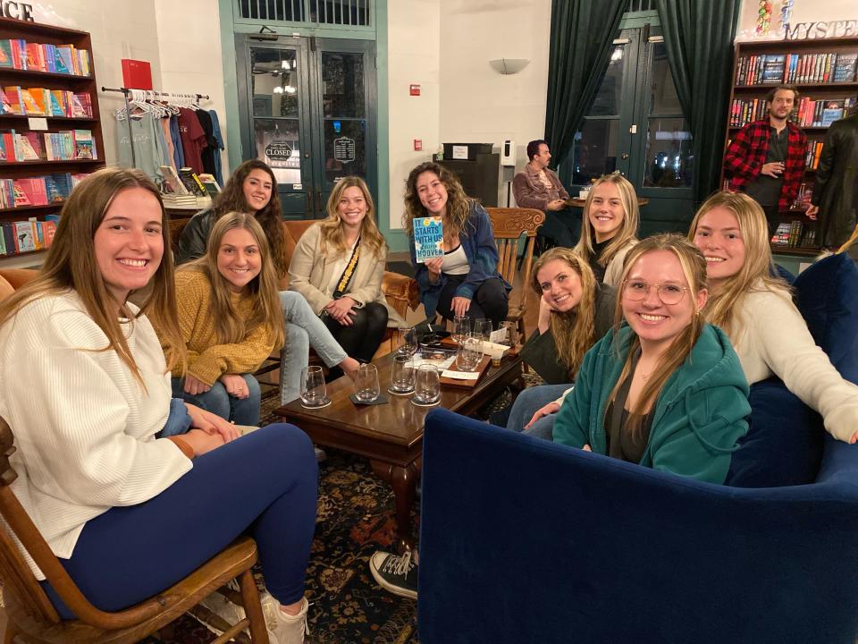 A group of girls during book club, sitting around a table and smiling at the camera.