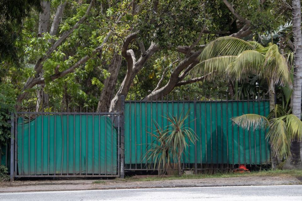 Lush greenery and trees surround a fence.