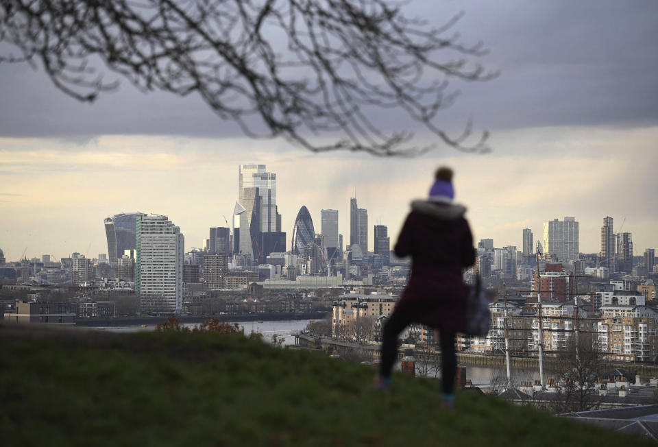 A woman looks out over the city of London over the River Thames, from Greenwich Park in London, Friday Jan. 22, 2021.  Temperatures could drop as low as minus 10C in the coming days, according to predictions as Storm Christoph gives way to colder winter weather this weekend.(Stefan Rousseau/PA via AP)