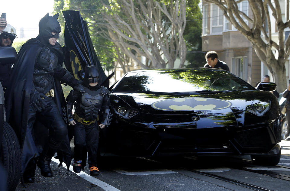 Miles Scott, dressed as Batkid, second from left, exits the Batmobile with Batman to save a damsel in distress in San Francisco, Friday, Nov. 15, 2013. San Francisco turned into Gotham City on Friday, as city officials helped fulfill Scott's wish to be "Batkid." Scott, a leukemia patient from Tulelake in far Northern California, was called into service on Friday morning by San Francisco Police Chief Greg Suhr to help fight crime, The Greater Bay Area Make-A-Wish Foundation says. (AP Photo/Jeff Chiu)