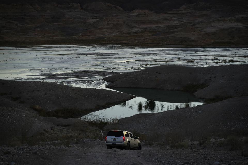 FILE - A car drives along a dirt road near Lake Mead at the Lake Mead National Recreation Area, Friday, Jan. 27, 2023, near Boulder City, Nev. A Native American tribe in Arizona has reached a deal with the U.S. government not to use some of its Colorado River water rights in return for $150 million and funding for a pipeline project. (AP Photo/John Locher, File)