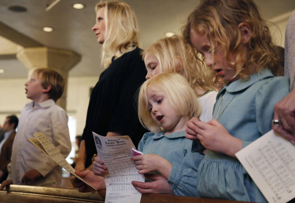 In this Feb. 9, 2020, photo, the family of Catholic Priest Joshua Whitfield, from left, Peter, 8, his wife, Alli, and daughters Maggie, 9, Bernadette, 4, and Zoe-Catherine, 5, stand together in a pew during Sunday Mass at St. Rita Catholic Community in Dallas. In 2009 the Whitfields, who were Episcopalian, converted to Catholicism and Josh Whitfield was ordained as a priest less than three years later. (AP Photo/Jessie Wardarski)