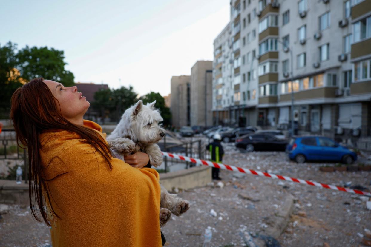 A woman with a dog looks at her apartment building heavily damaged during a massive Russian drone strike (REUTERS)