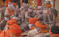 Naga Sadhu or Naked Hindu holy men wait for the start of a procession towards the river Ganges for Shahi snan or a Royal bath during Kumbh mela, in Haridwar in the Indian state of Uttarakhand, Monday, April 12, 2021. As states across India are declaring some version of a lockdown to battle rising Covid cases as part of a nationwide second-wave, thousands of pilgrims are gathering on the banks of the river Ganga for the Hindu festival Kumbh Mela. The faithful believe that a dip in the waters of the Ganga will absolve them of their sins and deliver them from the cycle of birth and death. (AP Photo/Karma Sonam)