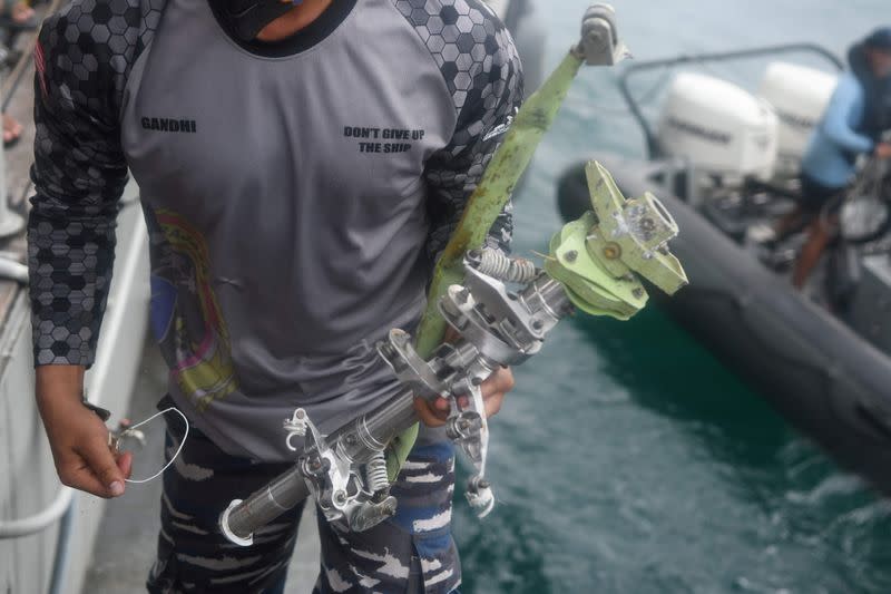 Indonesian navy personnel carries a recovered piece of debris from Sriwijaya Air flight SJ 182, which crashed into the sea, onboard Naval warship KRI Rigel (933) during the search and rescue operation at sea off the Jakarta coast