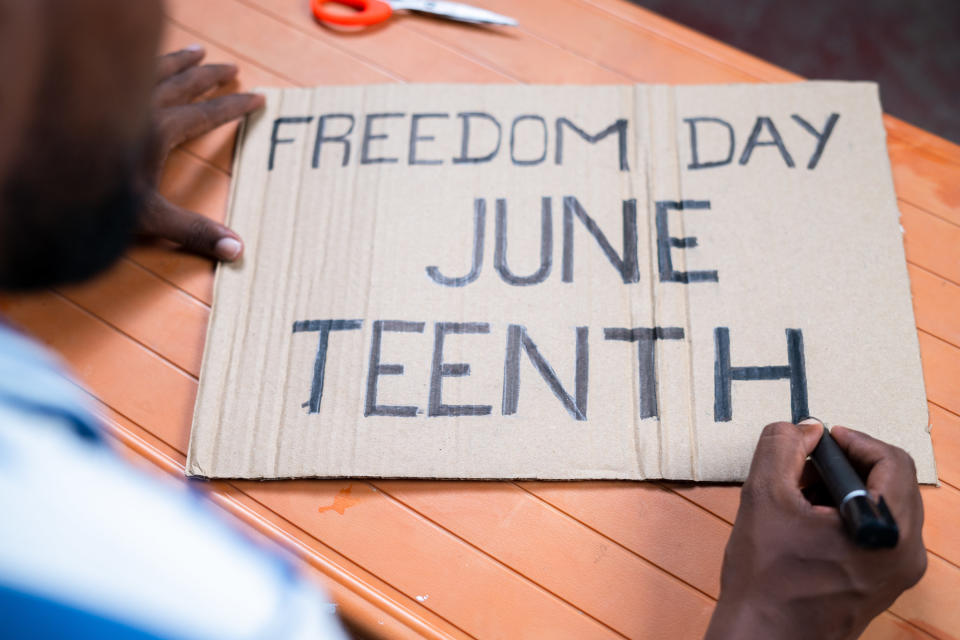 a man writes a juneteenth sign