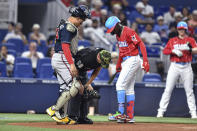 Miami Marlins Jazz Chisholm Jr., right, and Atlanta Braves catcher Travis d'Arnaud, left, check on home plate umpire Jansen Visconti after he was struck by a foul ball during the first inning of a baseball game Saturday, May 21, 2022, in Miami. (AP Photo/Gaston De Cardenas)