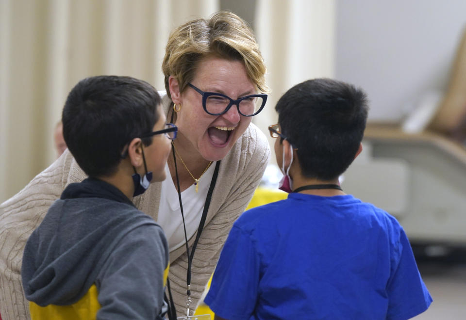 Melinda Kavanaugh, center, a University of Wisconsin-Milwaukee social work professor, lets out a laugh while talking with Ronan Kotiya, 11, and his brother Keaton Kotiya, 9, during a workshop for young caregivers of ALS family members in Dallas, Texas, Saturday, April 9, 2022. Kavanaugh thinks as many as 10 million children are involved in caregiving in the U.S. and says youth caregiving will grow as the U.S. population ages and chronic health problems like diabetes become more common. She and other researchers say young caregivers provide crucial help to their families, and they need more support. (AP Photo/LM Otero)