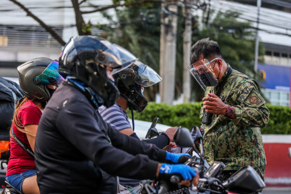 封城後，一名軍人在菲律賓街頭檢查市民是否遵守防疫規定。   圖 : 翻攝自新華社