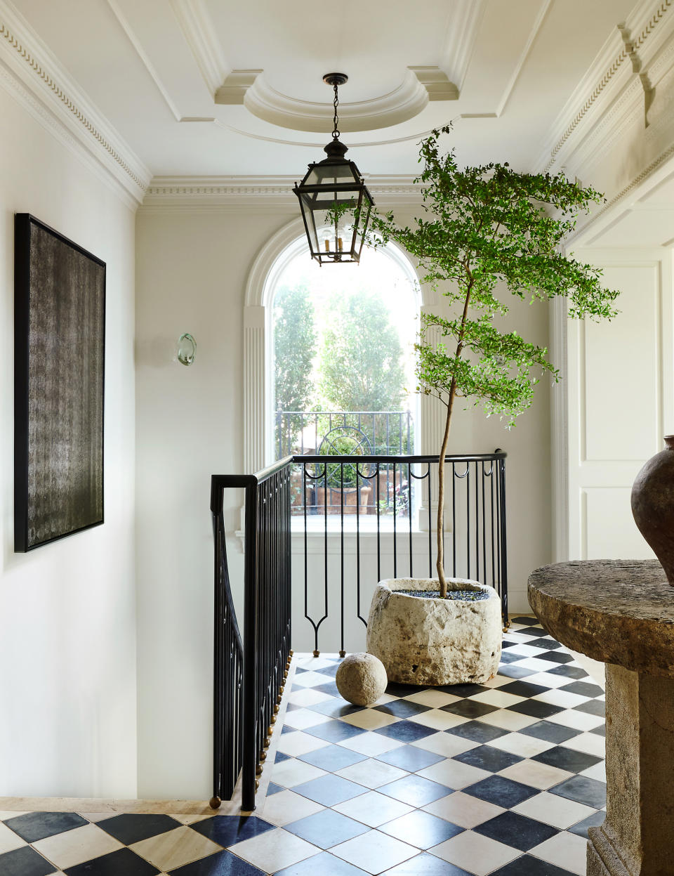 a hallway with a large tree in a stone planter