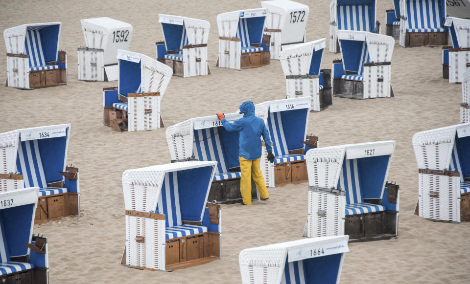 A man arranges beach chairs in the rain on the North Sea island of Sylt, Sundau, June 20, 2021. (Daniel Bockwoldt/dpa via AP)