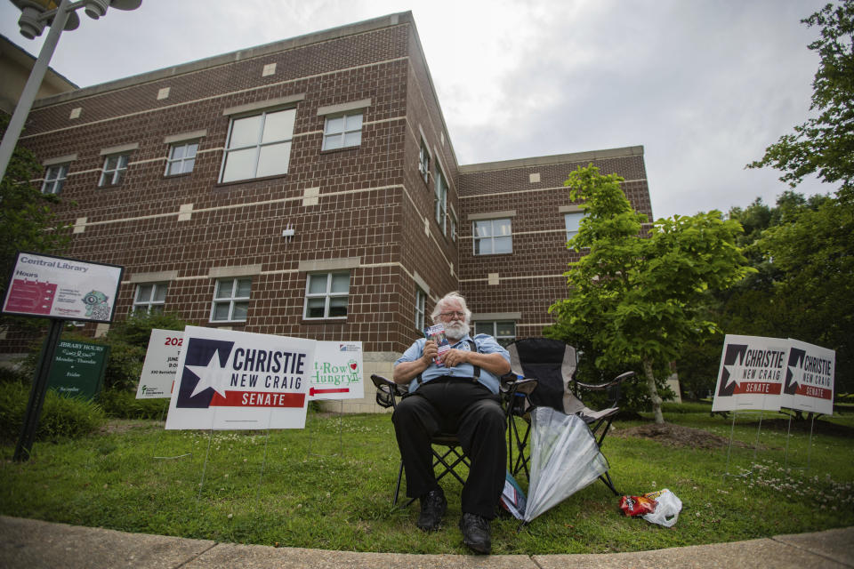 Volunteer Buzz Hartmann waits for potential voters to talk to about Virginia's Senate Republican Primary race outside a Republican primary polling location at Chesapeake Central Library on Tuesday, June 20, 2023, in Chesapeake, Va. (Tess Crowley/The Virginian-Pilot via AP)