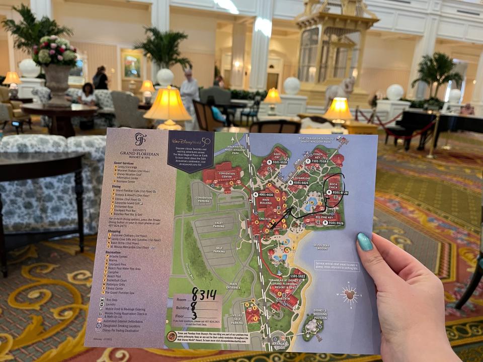 hand holding up an illustrated map of the grand floridian resort at disney world in the resort lobby