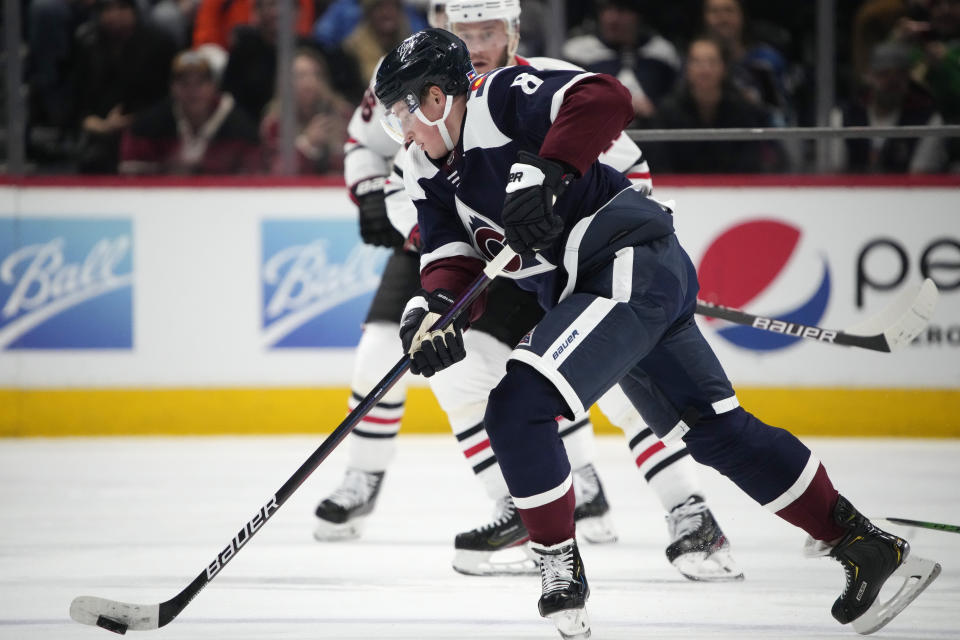 Colorado Avalanche defenseman Cale Makar, front, collects the puck as Chicago Blackhawks center Jonathan Toews defends in the second period of an NHL hockey game Monday, Jan. 24, 2022, in Denver. (AP Photo/David Zalubowski)