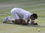 Novak Djokovic of Serbia eats some grass after defeating Roger Federer of Switzerland in their men's singles final tennis match at the Wimbledon Tennis Championships, in London July 6, 2014. REUTERS/Suzanne Plunkett (BRITAIN - Tags: SPORT TENNIS)