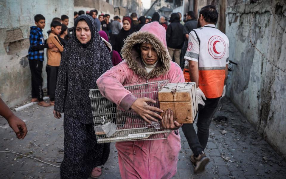 A girl carrying a bird cage reacts as people flee following an Israeli strike in Rafah