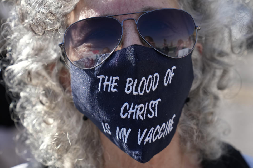 A protester shows a mask during a rally to protest measures imposed against people who are not vaccinated, in Beirut, Lebanon, Saturday, Jan. 8, 2022. Vaccination is not compulsory in Lebanon but in recent days authorities have become more strict in dealing with people who are not inoculated or don’t carry a negative PCR test. (AP Photo/Hussein Malla)