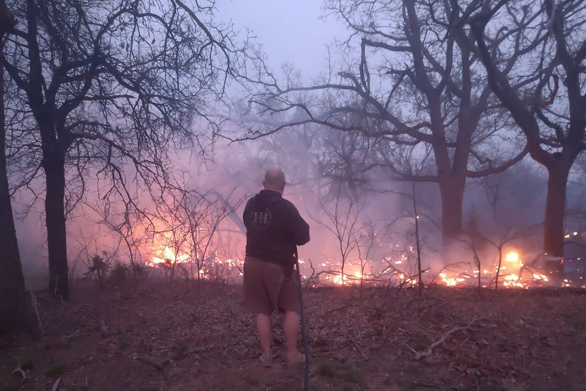 Jim Garinger, fights a fire outside his home built by his great-grandfather, March 31, 2023, in Guthrie, Oklahoma. Garinger and his family were able to save his family home with the help of firefighters. Extremely dry conditions in Oklahoma combined with high winds to fuel several large wildfires that forced interstate closures and sent residents fleeing from their homes (Jessica Garinger via AP) (Jessica Garinger)