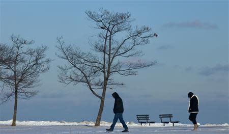 Residents brave the cold as they walk along the shores of Lake Michigan as another round of arctic air blasts the midwest keeping the wind chill in the negative numbers, in Milwaukee, Wisconsin February, 6, 2014. REUTERS/Darren Hauck