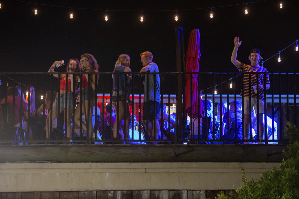 Patrons stand on the Bear Trap's rooftop bar on The Strip, the University of Alabama's bar scene, Saturday, Aug. 15, 2020, in Tuscaloosa, Ala. More than 20,000 students returned to campus for the first time since spring break, with numerous school and city codes in effect to limit the spread of COVID-19. (AP Photo/Vasha Hunt)