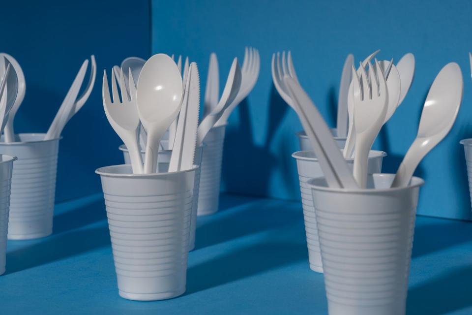 used disposable plastic tableware environmental problem, environmental pollution cutlery and glasses on a blue background