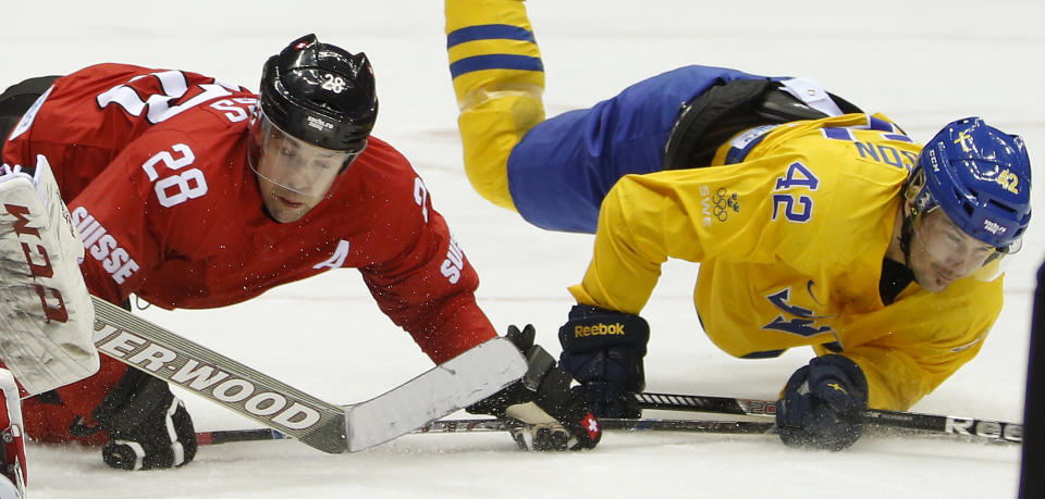 Switzerland forward Martin Pluss (28) and Sweden forward Jimmie Ericsson fall to the ice in the third period of a men's ice hockey game at the 2014 Winter Olympics, Friday, Feb. 14, 2014, in Sochi, Russia. Sweden won 1-0. (AP Photo/Mark Humphrey)