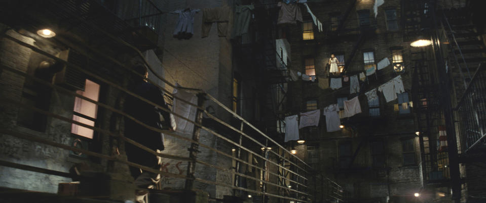 Maria up high on a fire escape looking down at Tony who approaches down the alleyway