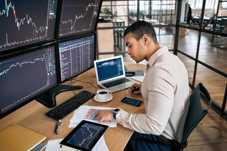 An investor looking at several monitors on his desk.