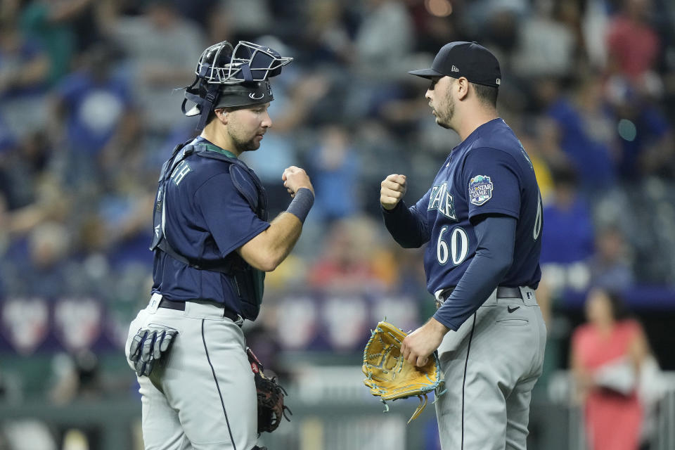 Seattle Mariners relief pitcher Tayler Saucedo (60) and catcher Cal Raleigh celebrate after their baseball game against the Kansas City Royals Tuesday, Aug. 15, 2023, in Kansas City, Mo. The Mariners won 10-8 in 10 innings. (AP Photo/Charlie Riedel)