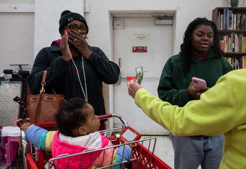 A Secret Santa elf gives a $100 bill to Barbara Watkins, 48, and Raionna Walker, 22, inside The Salvation Army during the annual Secret Santa in Lincoln Park on Thursday, Dec. 14, 2023.