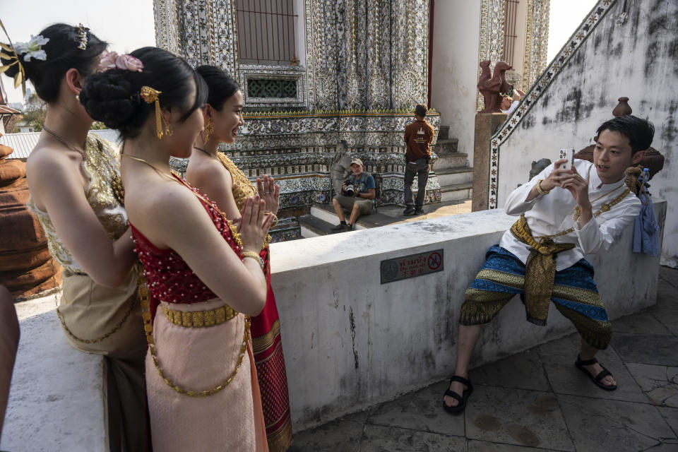Chinese tourists in Thai traditional dress pose for a photograph at Wat Arun Ratchawararam Rathawaramahawihan in Bangkok. (Photo: Sirachai Arunrugst/Bloomberg)