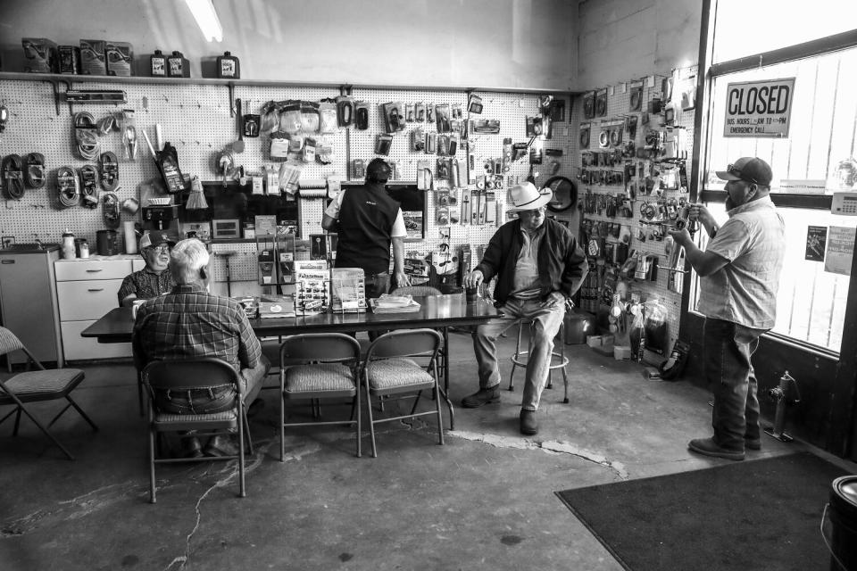 People, some seated in folding chairs, around a table inside a store.