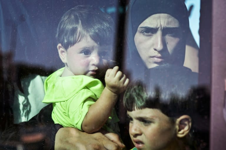 A migrant family boards a bus after disembarking from a Greek government-chartered ferry at the port of Piraeus in Athens on August 25, 2015