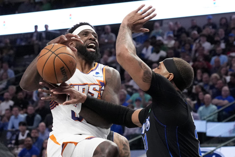 Phoenix Suns forward Royce O'Neale, left, loses control of the ball on a drive to the basket as Dallas Mavericks' Daniel Gafford, right, defends in the first half of an NBA basketball game in Dallas, Thursday, Feb. 22, 2024. (AP Photo/Tony Gutierrez)