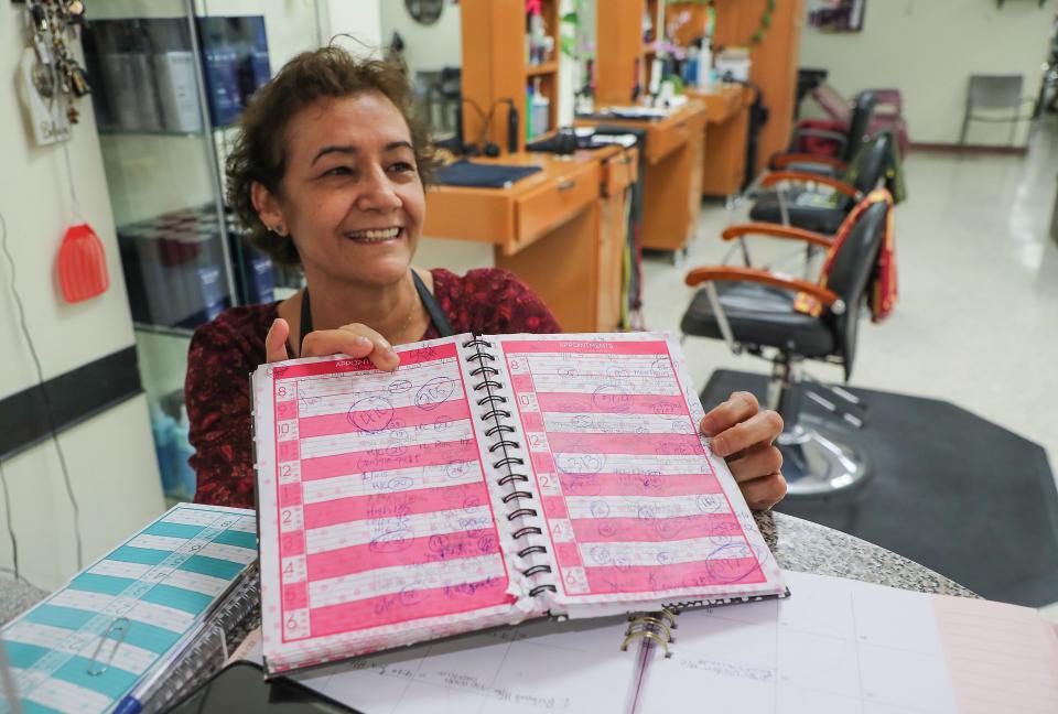 Monica Fausto smiles as she shows off a full appointment book at the Lotus 2 Hair Salon which she owns in the Indio Grand Marketplace in Indio, Calif., April 28, 2022.