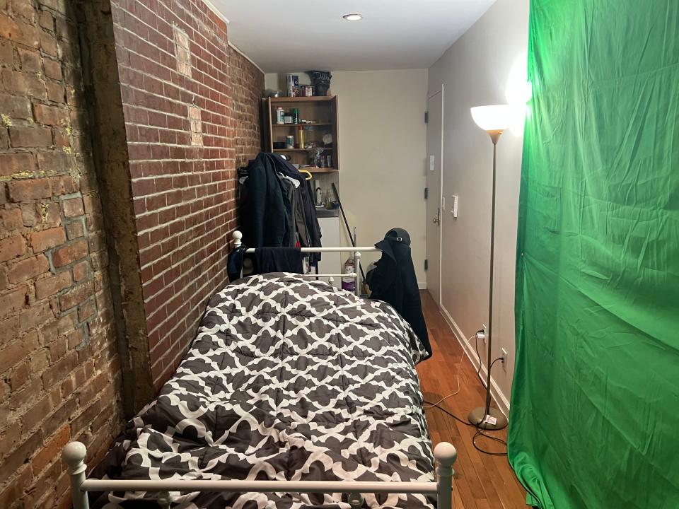 A view of Ron Ervin&#39;s Harlem apartment with a single bed and green backdrop.