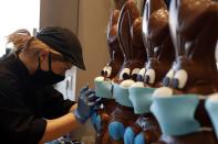 An employee of cake shop prepares chocolate Easter bunnies with masks in Lykovrisi, northern Athens, on Wednesday, April 8, 2020. Cake shops and bakeries in Greece have remained open during a strict circulation ban in Greece to contain the spread of the COVID-19, but authorities have intensified a crackdown on lockdown violations ahead of Easter, which is celebrated by Orthodox Christians on April 19. Greece's Orthodox Church says it will not permit any public gatherings for Easter services. (AP Photo/Thanassis Stavrakis)