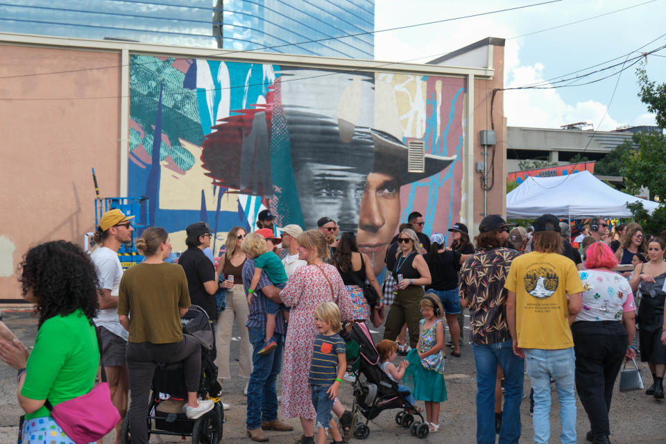 The crowd enjoys the music and sights in front of a mural of Hank Williams Jr. by Malcolm Byers Saturday at the 4th annual Hoodoo Music Festival in downtown Amarillo.