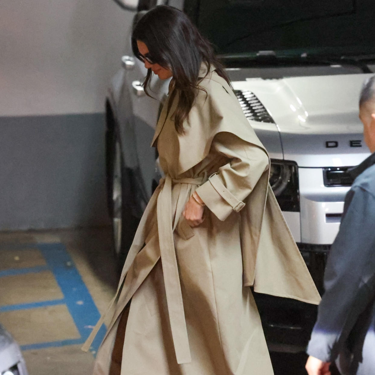  Kendall Jenner wearing a tan trench coat with black trousers and black pointed toe heels . 