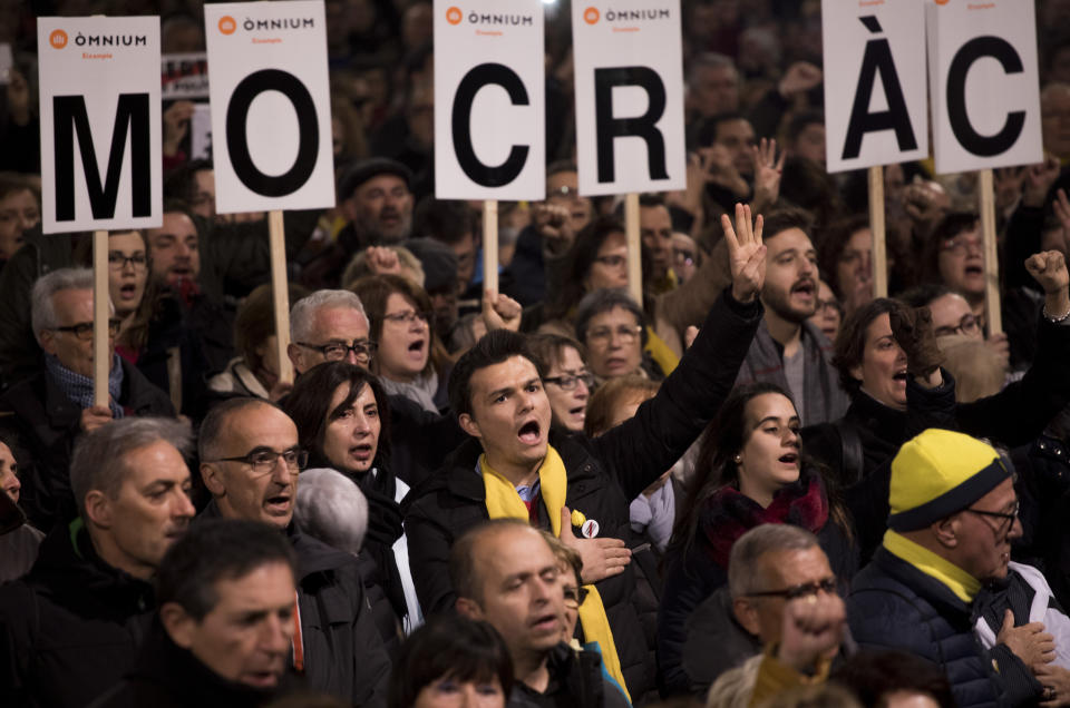 Pro independence demonstrators sign the national anthem during a protest in Catalonia square in Barcelona, Spain, Tuesday, Feb. 12, 2019. A sensitive trial against a dozen Catalan separatist politicians and activists got underway Tuesday in Spain's Supreme Court amid protests by pro-independence supporters and a highly volatile political environment. Banner in Catalan reads "freedom politics imprisoned". (AP Photo/Emilio Morenatti)