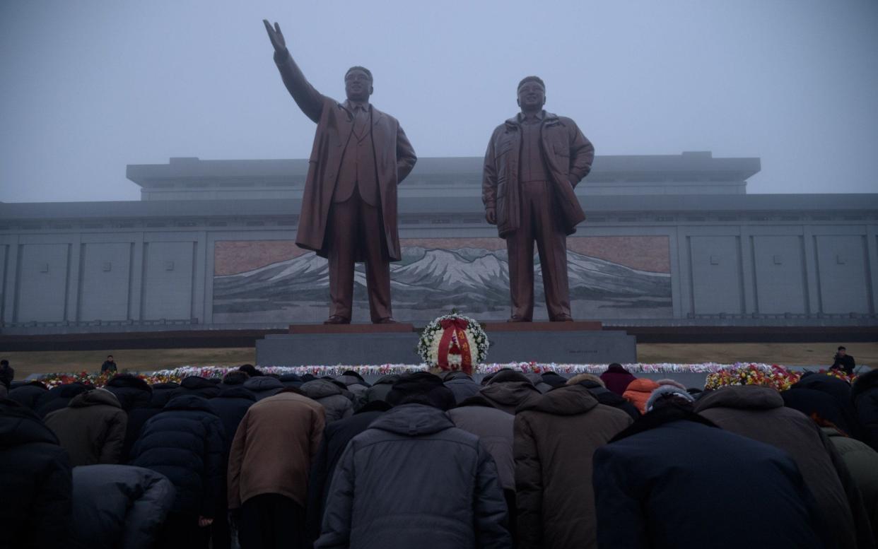 North Koreans bow before a statue of lateleader Kim Jong-il, on the anniversary of his death - AFP