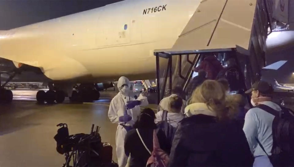 In this image from a video taken on Monday, Feb. 17, 2020, U.S. passengers who evacuated off the quarantined cruise ship the Diamond Princess, board a Kalitta Air plane bound for the U.S., at Haneda airport in Tokyo.(Cheryl and Paul Molesky via AP)