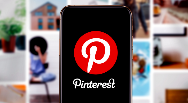 Smart phone with the Pinterest (PINS) logo in front of blurred out pinterest post pictures, Pinterest layoffs