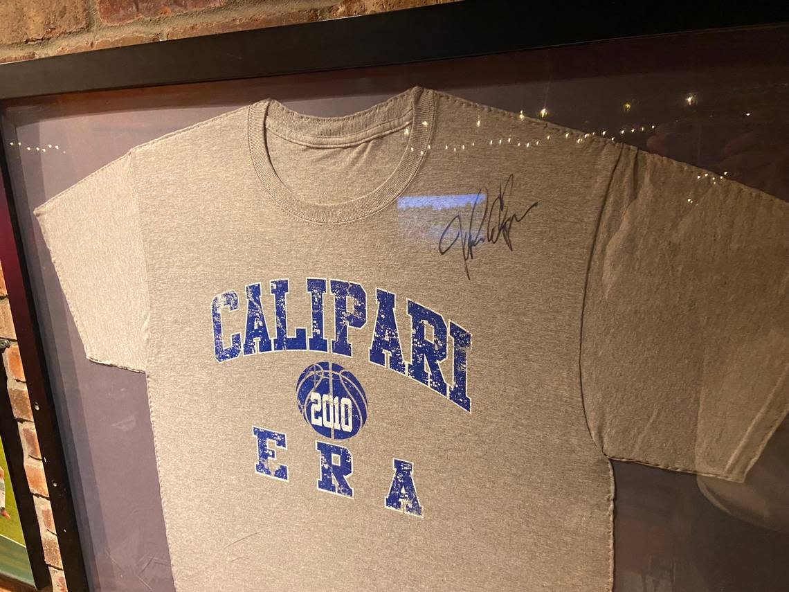 A framed “Calipari Era” T-shirt from 2010 featuring a signature on it from John Calipari hangs in the stairway of Jack Demsey’s in New York City. The establishment of the bar and restaurant as the home base for the New York City UK Alumni Club coincided with Calipari’s arrival at Kentucky.